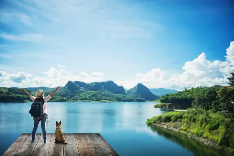 Fünf ungewöhnliche Reiseziele mit Hund - Person mit Hund steht auf einem Steg mit Blick auf das Wasser